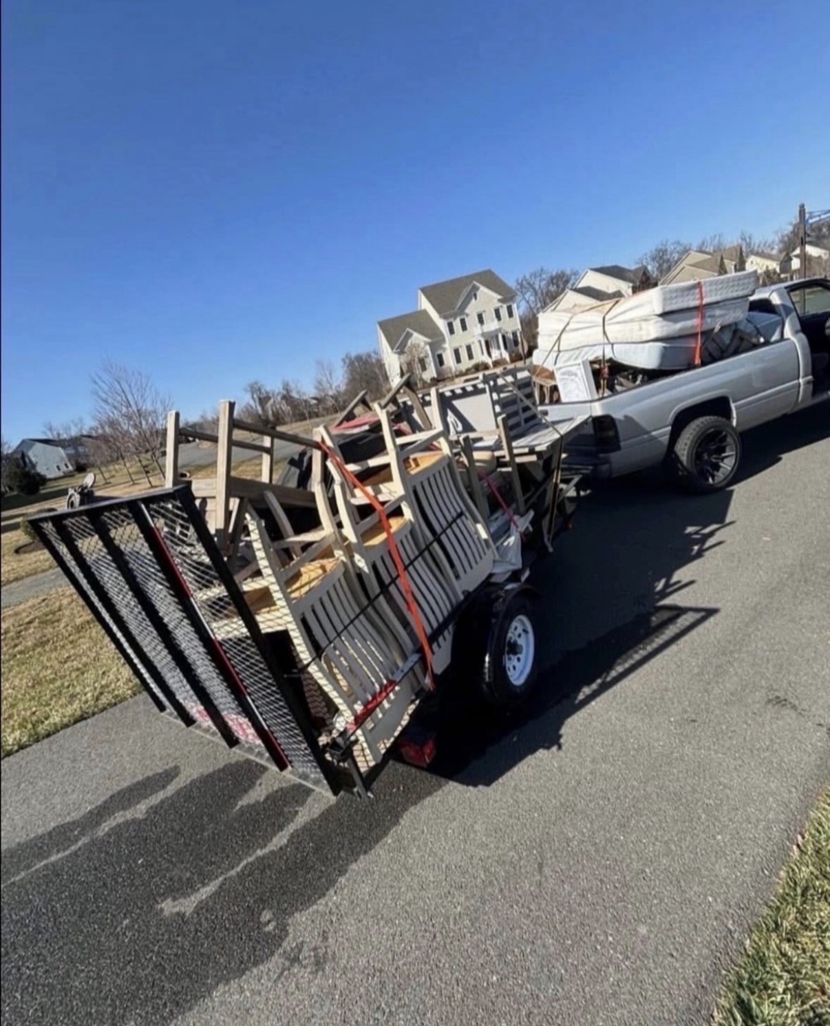 Truck and trailer loaded with furniture and mattresses on a residential street